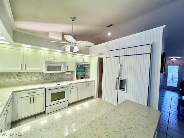 kitchen featuring pendant lighting, white appliances, vaulted ceiling, and white cabinets