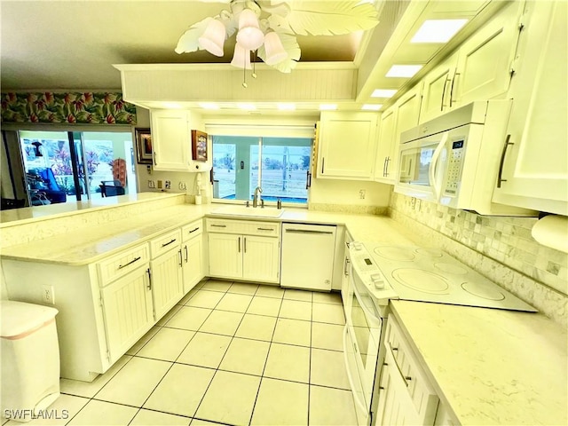 kitchen with light tile patterned floors, white appliances, white cabinets, and kitchen peninsula