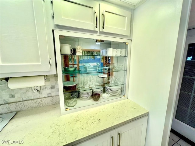 bar with light stone counters, white cabinetry, and tasteful backsplash