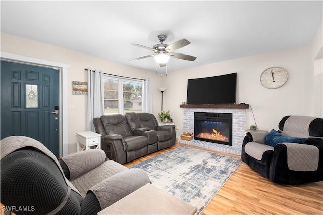 living room featuring light hardwood / wood-style floors, a brick fireplace, and ceiling fan