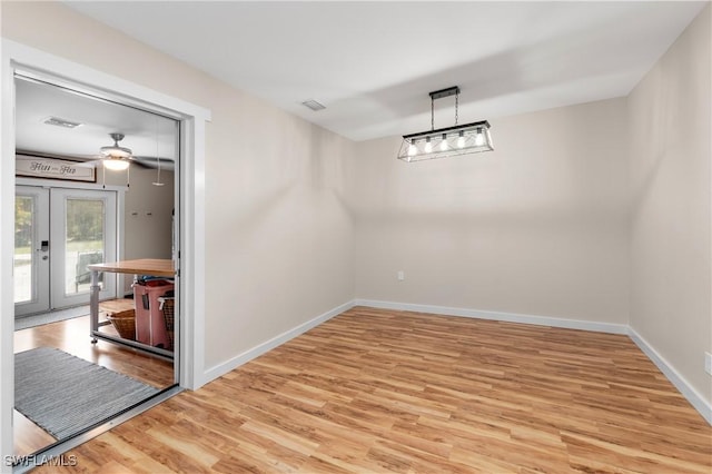 unfurnished dining area featuring ceiling fan, french doors, and light hardwood / wood-style floors