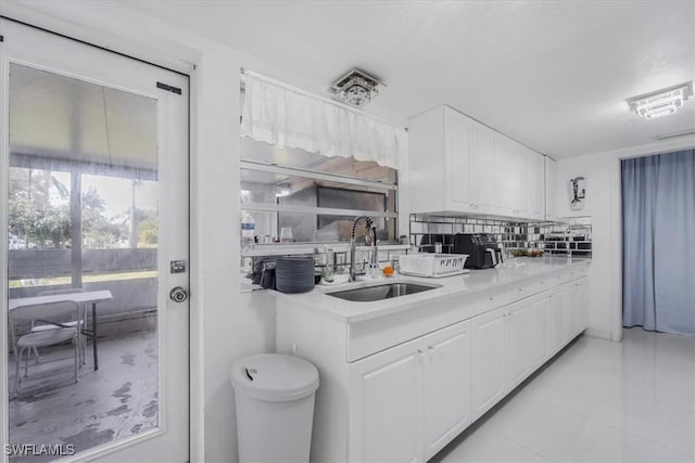 kitchen featuring tasteful backsplash, sink, white cabinetry, and light tile patterned flooring