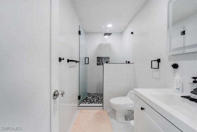 bathroom with toilet, vanity, and a shower with door