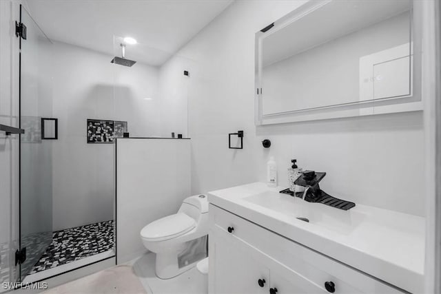 bathroom featuring toilet, vanity, and a shower with door