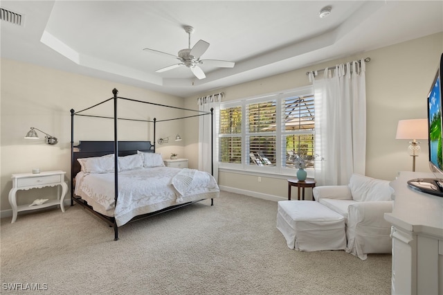 carpeted bedroom featuring ceiling fan and a tray ceiling