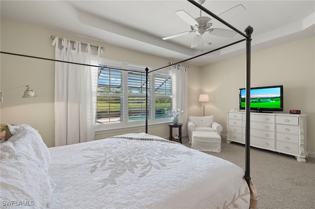 bedroom with carpet floors, ceiling fan, and a tray ceiling