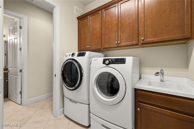 laundry room with cabinets, sink, light tile patterned floors, and washing machine and clothes dryer