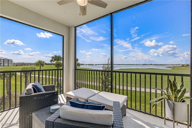 sunroom with ceiling fan and a water view