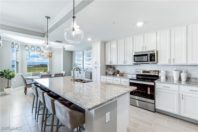 kitchen with white cabinetry, appliances with stainless steel finishes, a kitchen island with sink, and sink