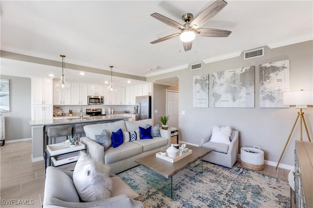 living room with sink, ornamental molding, and ceiling fan