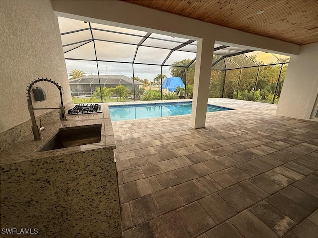 view of swimming pool with glass enclosure, sink, and a patio