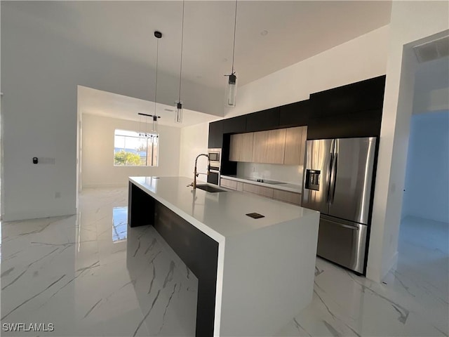 kitchen with sink, appliances with stainless steel finishes, decorative light fixtures, and an island with sink