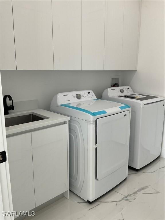 laundry area featuring cabinets, sink, and washer and dryer