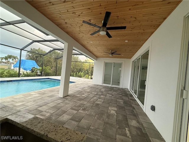 view of swimming pool featuring ceiling fan, glass enclosure, and a patio