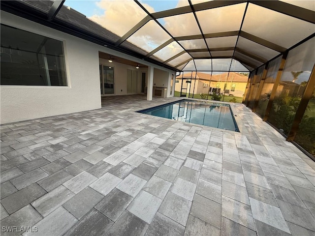 pool at dusk with a lanai and a patio