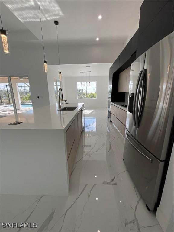 kitchen featuring sink, stainless steel fridge with ice dispenser, a large island with sink, plenty of natural light, and pendant lighting