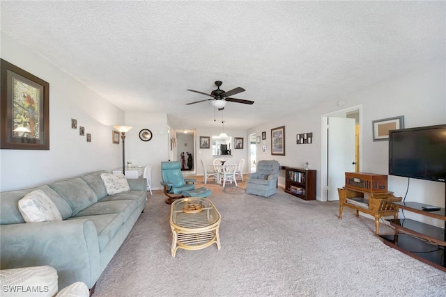 carpeted living room featuring ceiling fan and a textured ceiling