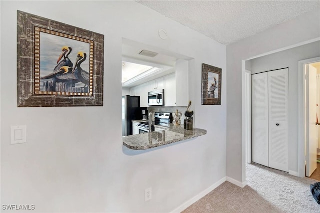 kitchen featuring tasteful backsplash, appliances with stainless steel finishes, a textured ceiling, light carpet, and white cabinets