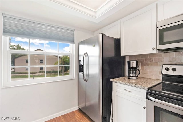 kitchen with white cabinets, appliances with stainless steel finishes, crown molding, and light hardwood / wood-style flooring