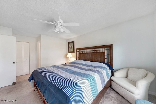 bedroom featuring ceiling fan, light colored carpet, a textured ceiling, and a closet