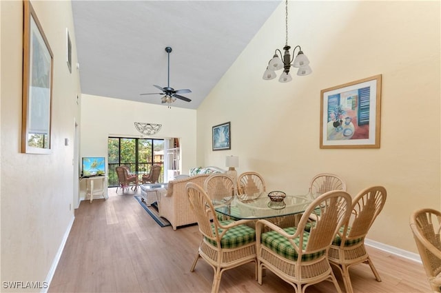 dining area with light hardwood / wood-style floors, high vaulted ceiling, and ceiling fan with notable chandelier