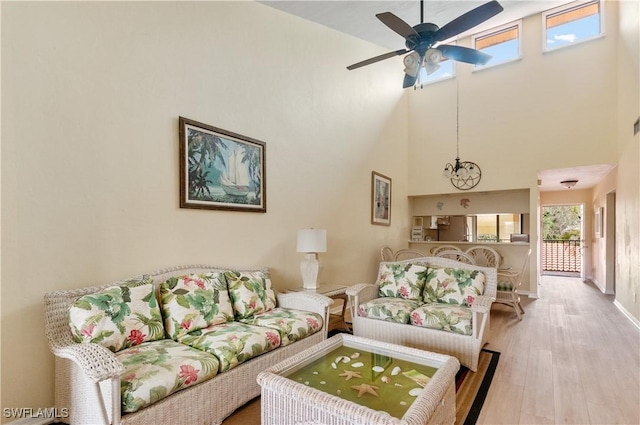 living room featuring hardwood / wood-style flooring, a high ceiling, and ceiling fan