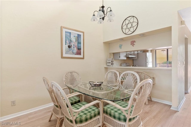 dining area with light hardwood / wood-style floors and a chandelier