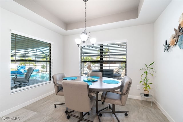 dining area with a notable chandelier, plenty of natural light, and a tray ceiling