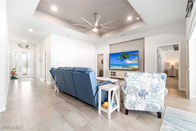 living room with ceiling fan and a raised ceiling