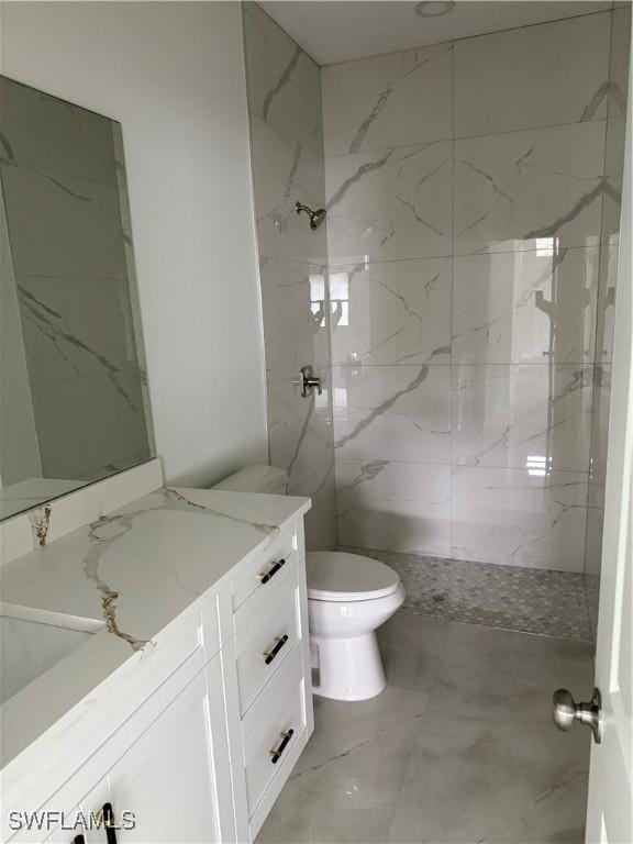 bathroom featuring toilet, tiled shower, and vanity