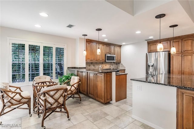 kitchen with appliances with stainless steel finishes, brown cabinets, visible vents, and a peninsula