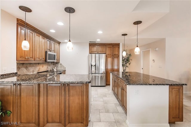 kitchen with brown cabinets, stainless steel appliances, decorative backsplash, dark stone counters, and a peninsula