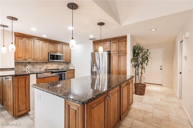 kitchen with stainless steel appliances, dark stone countertops, a center island, and pendant lighting