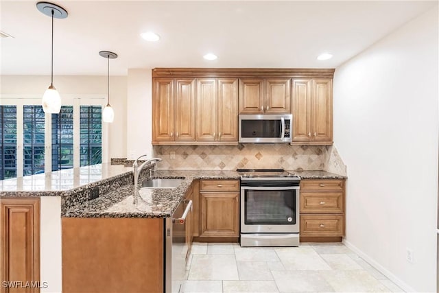 kitchen with backsplash, appliances with stainless steel finishes, stone countertops, a sink, and a peninsula