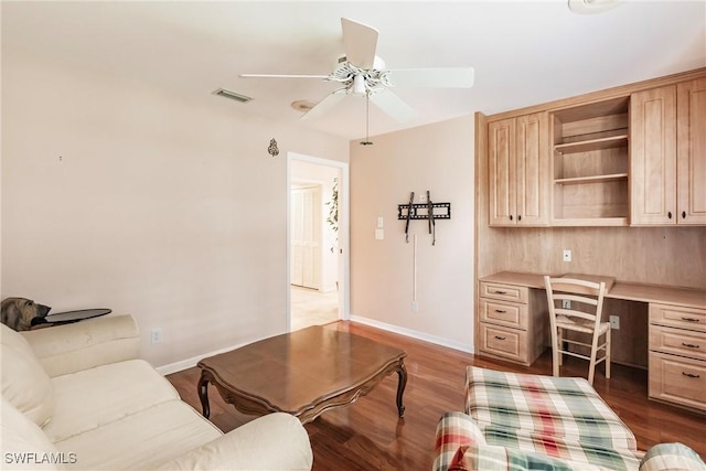 home office featuring ceiling fan, wood-type flooring, and built in desk