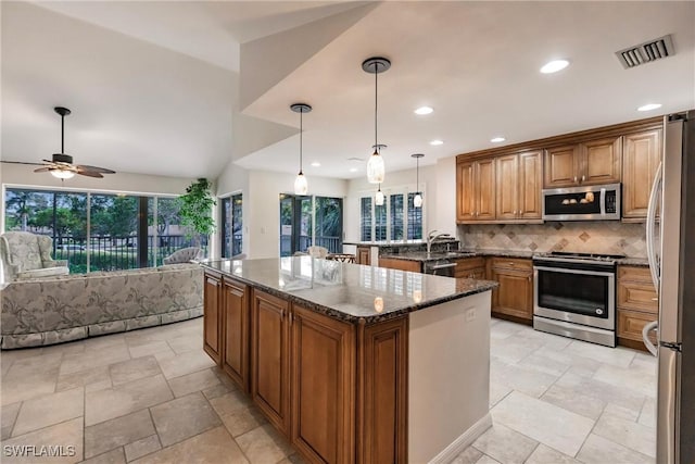 kitchen featuring visible vents, decorative backsplash, open floor plan, dark stone countertops, and stainless steel appliances