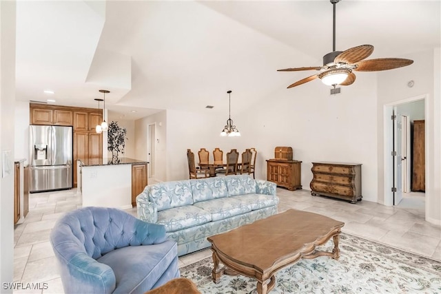 tiled living room featuring lofted ceiling and ceiling fan with notable chandelier