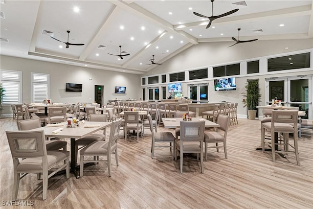 dining area with high vaulted ceiling and light hardwood / wood-style floors