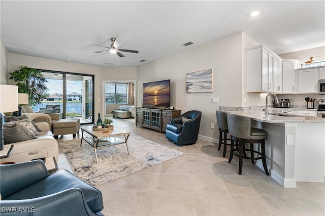 tiled living room with ceiling fan and sink