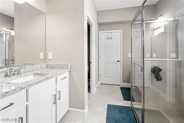 bathroom featuring a shower with shower door, vanity, and tile patterned flooring