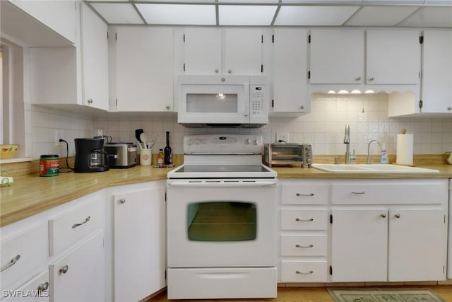 kitchen with white cabinets, decorative backsplash, sink, and white appliances