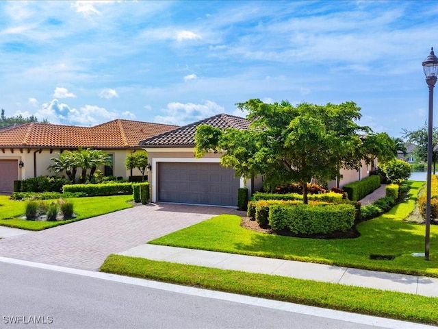 mediterranean / spanish-style home featuring a garage and a front lawn