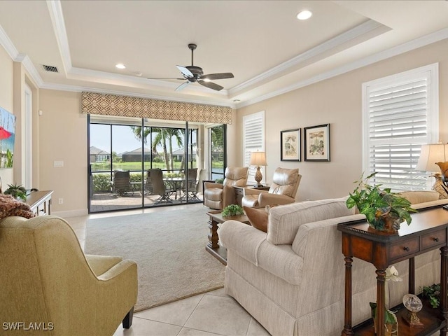 tiled living room featuring ceiling fan, ornamental molding, and a tray ceiling