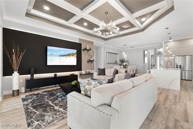 living room featuring sink, coffered ceiling, crown molding, an inviting chandelier, and light hardwood / wood-style flooring