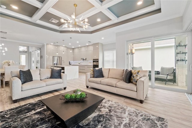 living room featuring an inviting chandelier, crown molding, coffered ceiling, and light hardwood / wood-style floors