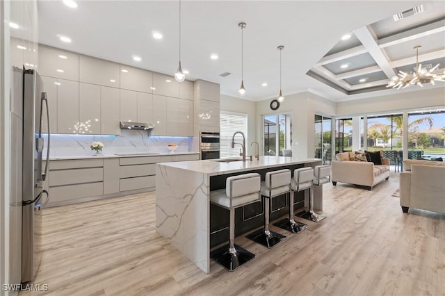 kitchen with decorative light fixtures, a breakfast bar area, stainless steel appliances, and a spacious island