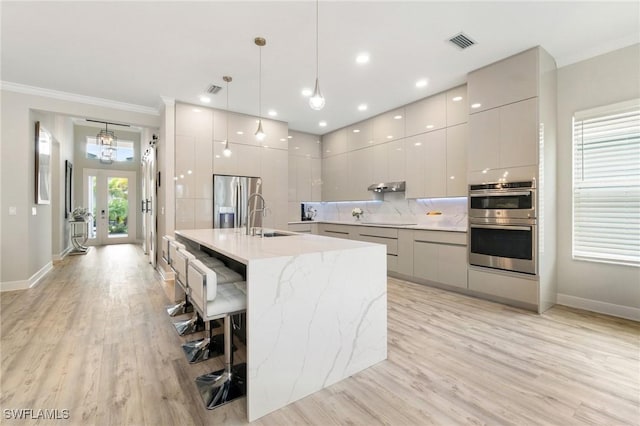 kitchen featuring stainless steel appliances, modern cabinets, backsplash, and visible vents