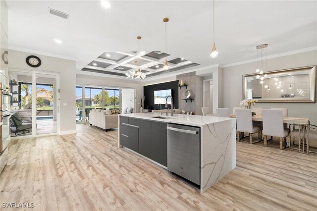 kitchen featuring coffered ceiling, appliances with stainless steel finishes, an island with sink, a notable chandelier, and pendant lighting