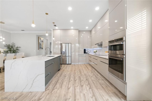 kitchen featuring sink, white cabinetry, a large island with sink, appliances with stainless steel finishes, and pendant lighting