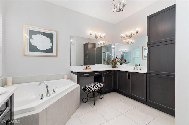 bathroom with tiled tub, vanity, tile patterned flooring, and a chandelier